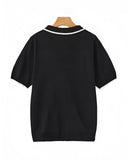 Black polo shirt on a wooden hanger with a white background