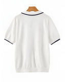 White polo shirt with black trim on a wooden hanger against a white background