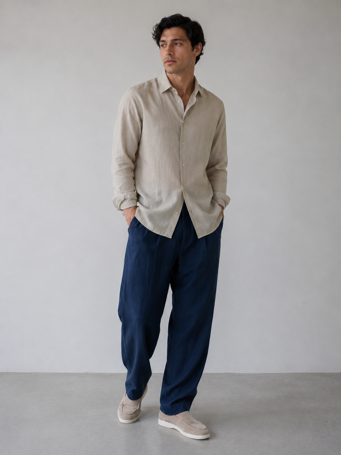 Man wearing a beige shirt and blue pants against a plain background