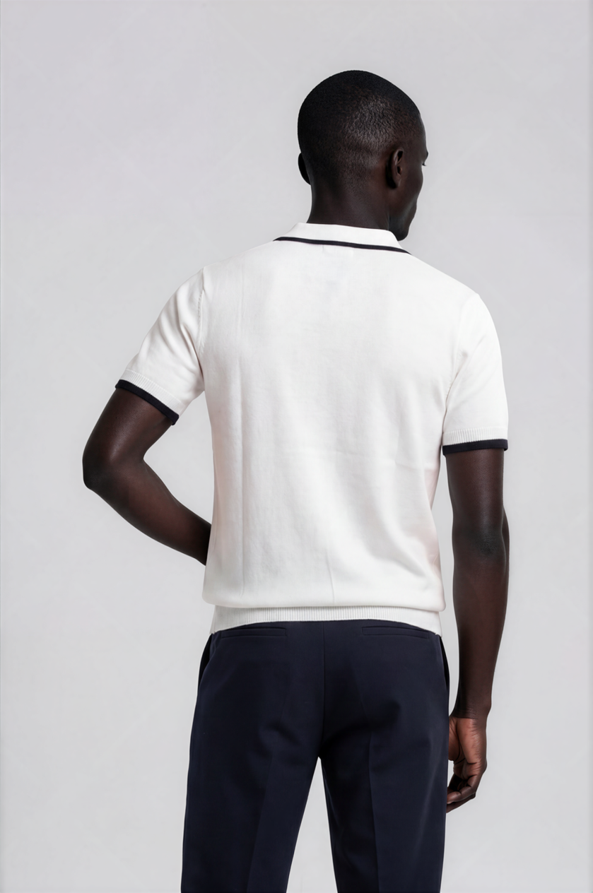 Person wearing a white polo shirt with black trim on a plain background