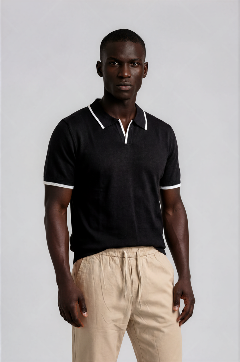 Man wearing a black polo shirt with white trim and beige pants on a light gray background