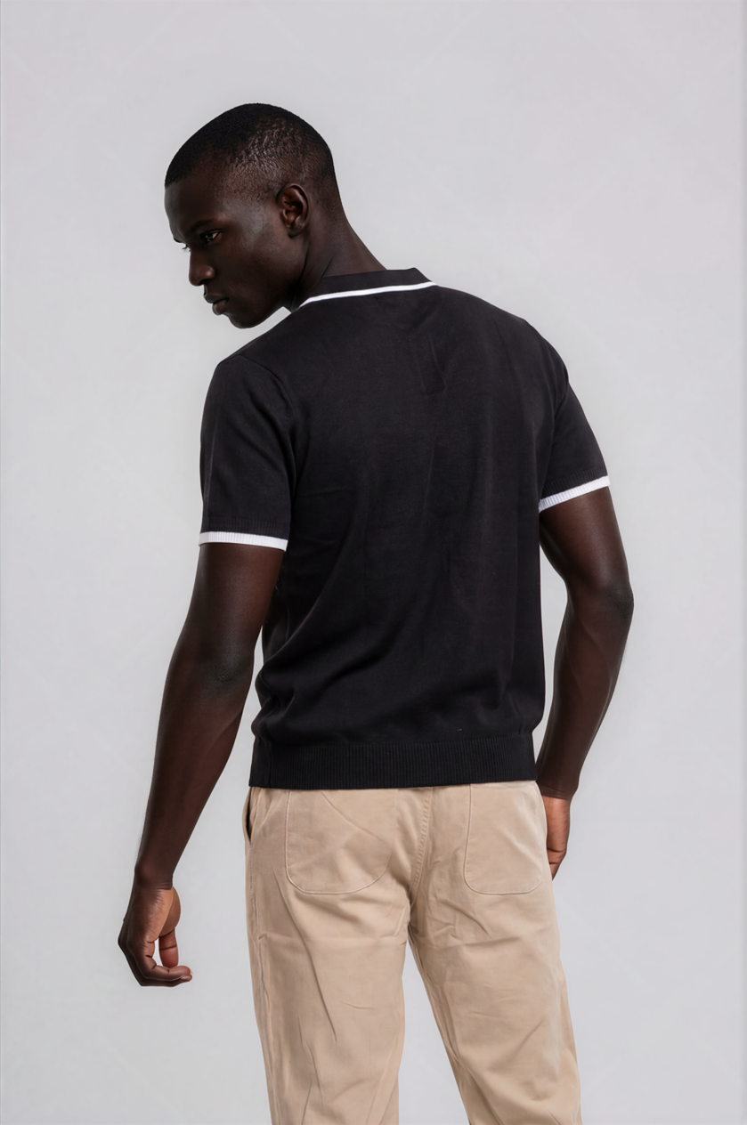 Man wearing a black polo shirt with white trim on a plain background